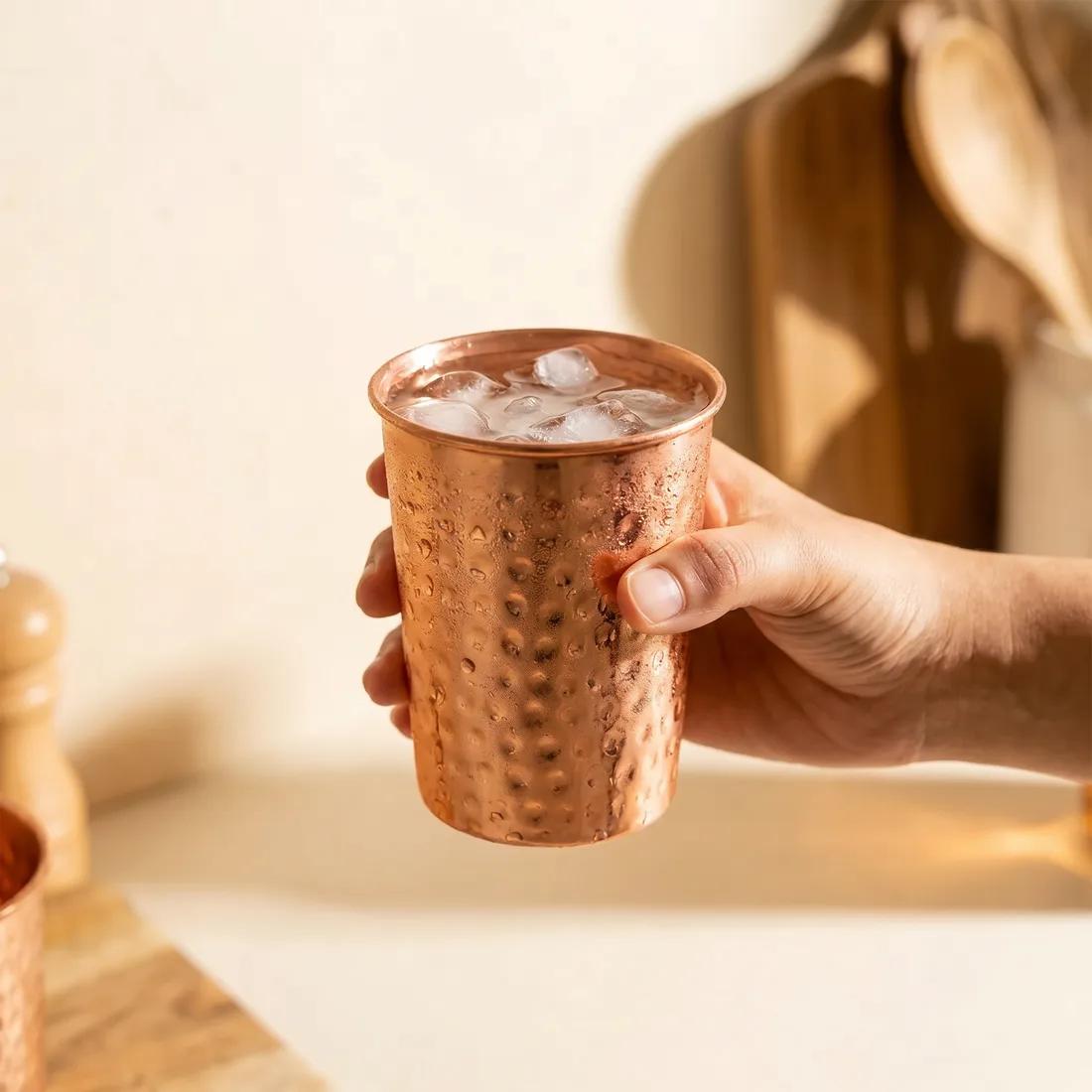Two hand-hammered Coppora copper cups on a wooden table.